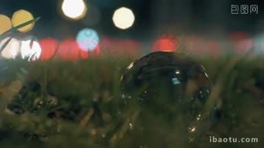 近景玻璃球在路边草地上与背景交通拍摄在夜晚的城市
